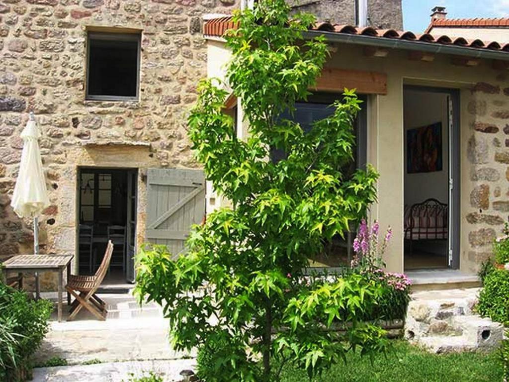 a tree in front of a house with a table at Gîte du Besset in Pradelles