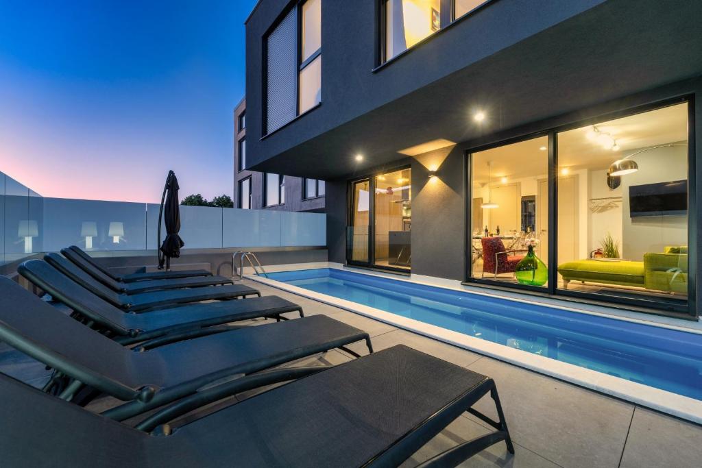 a swimming pool with lounge chairs and a house at Casa Seal by Briskva in Funtana