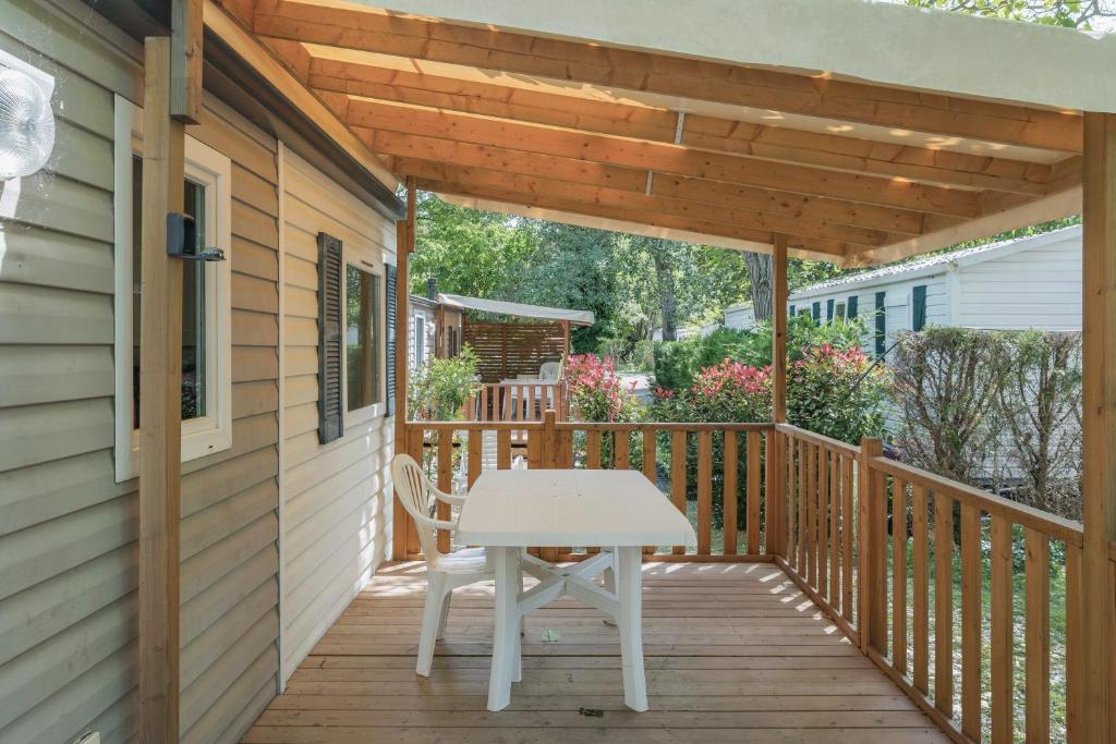 a wooden porch with a white table on a deck at Mobil-home - Le 147 aux Iscles in La Roque-dʼAnthéron