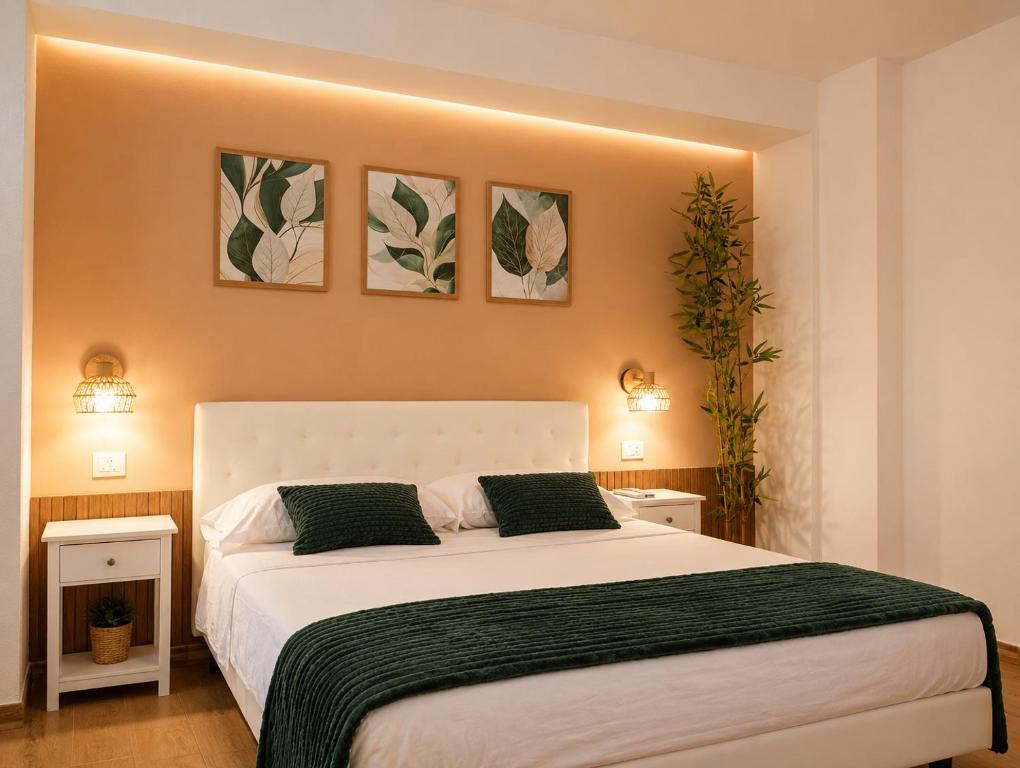 a bedroom with a large white bed with three pictures on the wall at Almarea Apartments in Santa Domenica