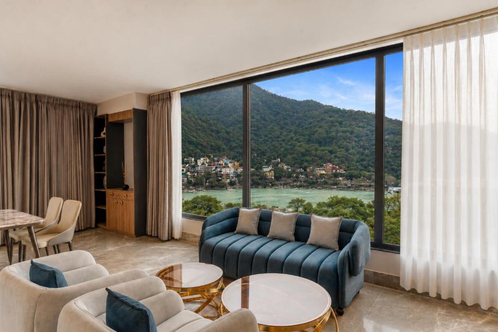 a living room with a couch and a large window at ZANA by the Ganges, Tapovan, Rishikesh in Rishīkesh