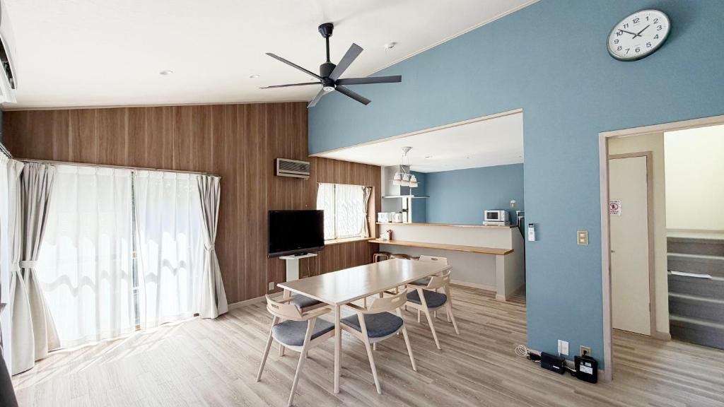 a dining room with a table and a clock on the wall at Villa Miura Beach -ヴィラ三浦海岸- in Miura
