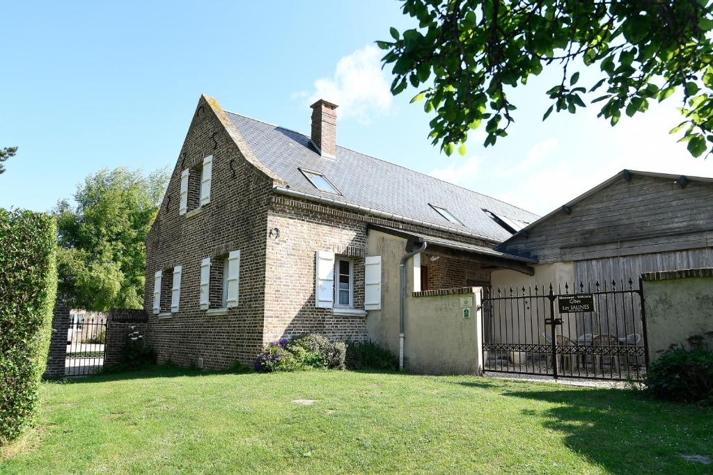 an old brick house with a fence in a yard at Gîte Lilas de mer in Ponthoile