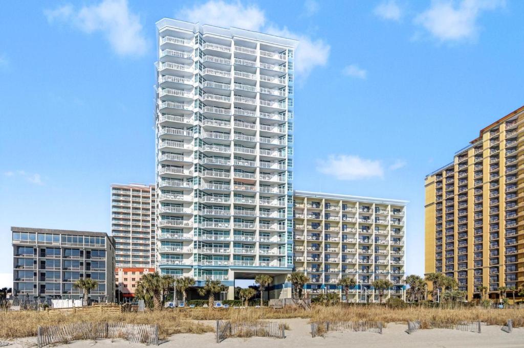a tall apartment building in front of some buildings at Carolinian Beach Resort in Myrtle Beach