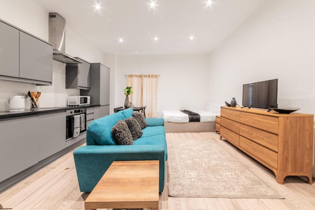 a living room with a blue couch and a bedroom at Sleeps 2 - Central - Studio - WiFi - Paid Parking in Maidstone