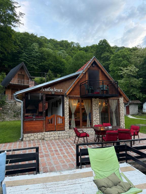 a log cabin with a table and red chairs at Ambijent house Patrijaha Pavla 22 in Železnička Stanica Ovčar Banja