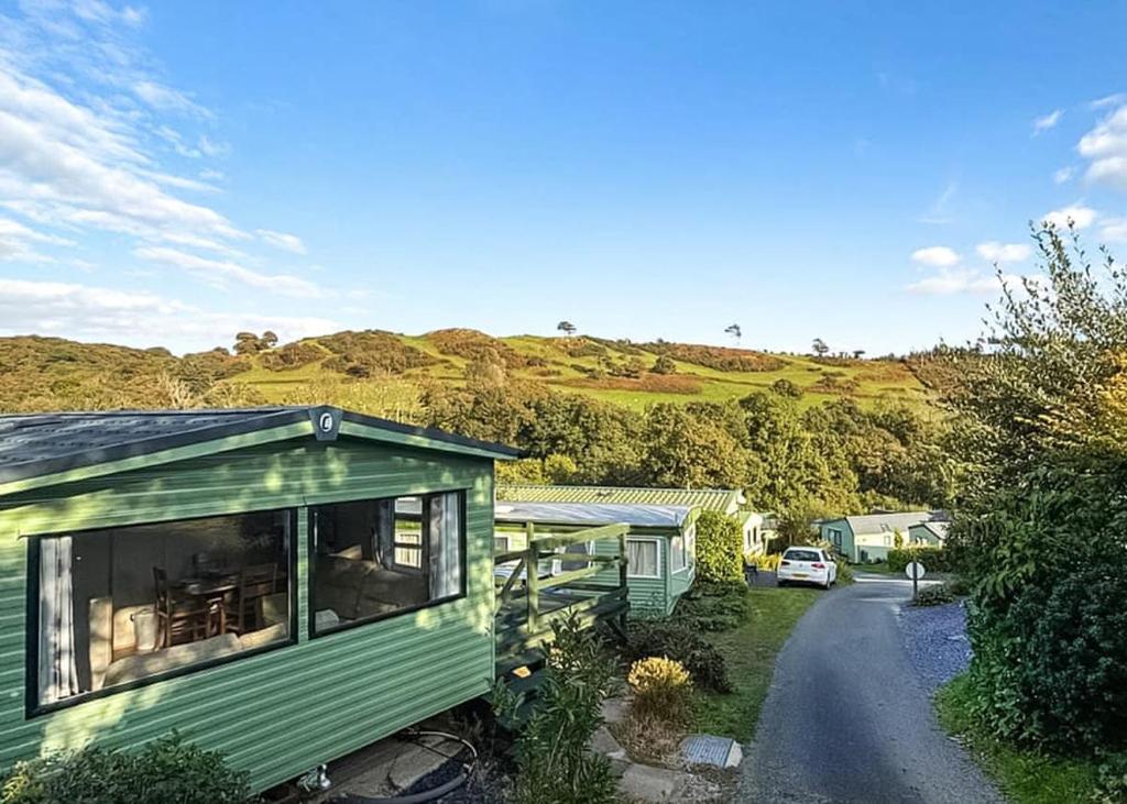a green tiny house sitting on the side of a road at Garth Holiday Park in Machynlleth