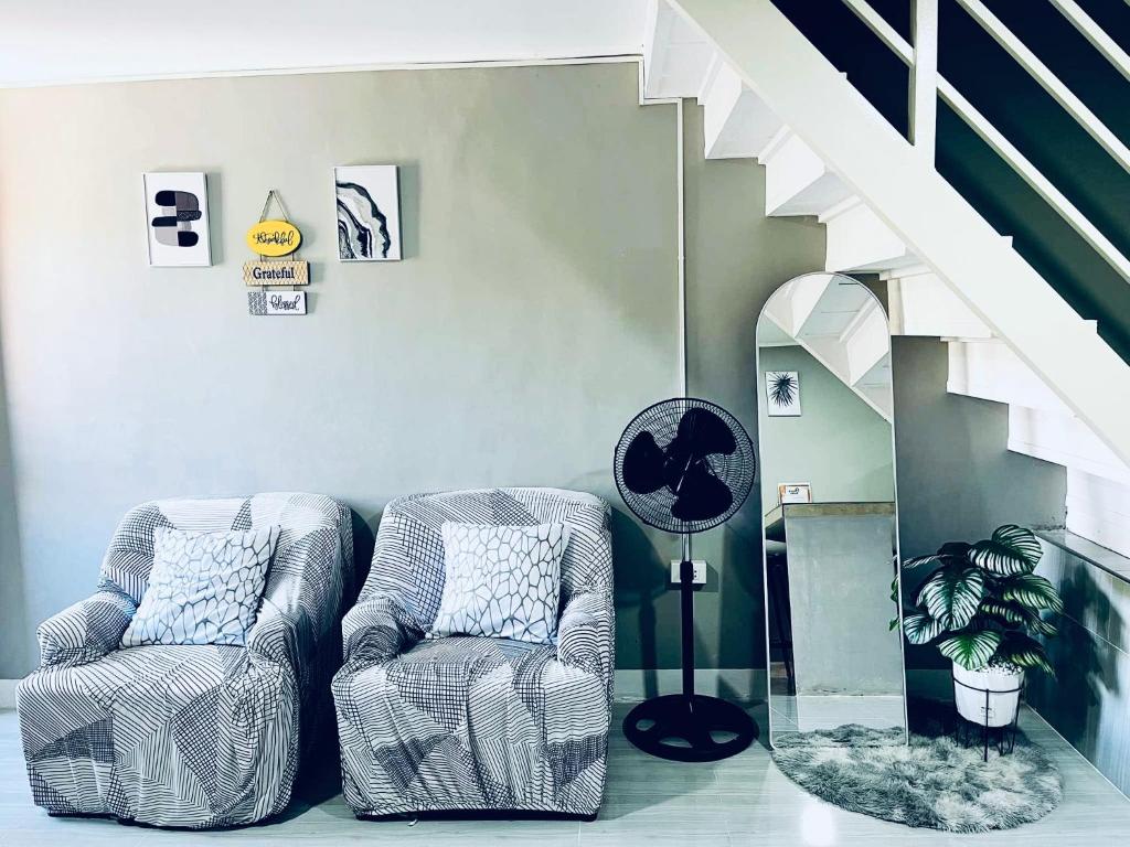 two chairs in a living room with a staircase at Khaleejay Transient House in Calapan