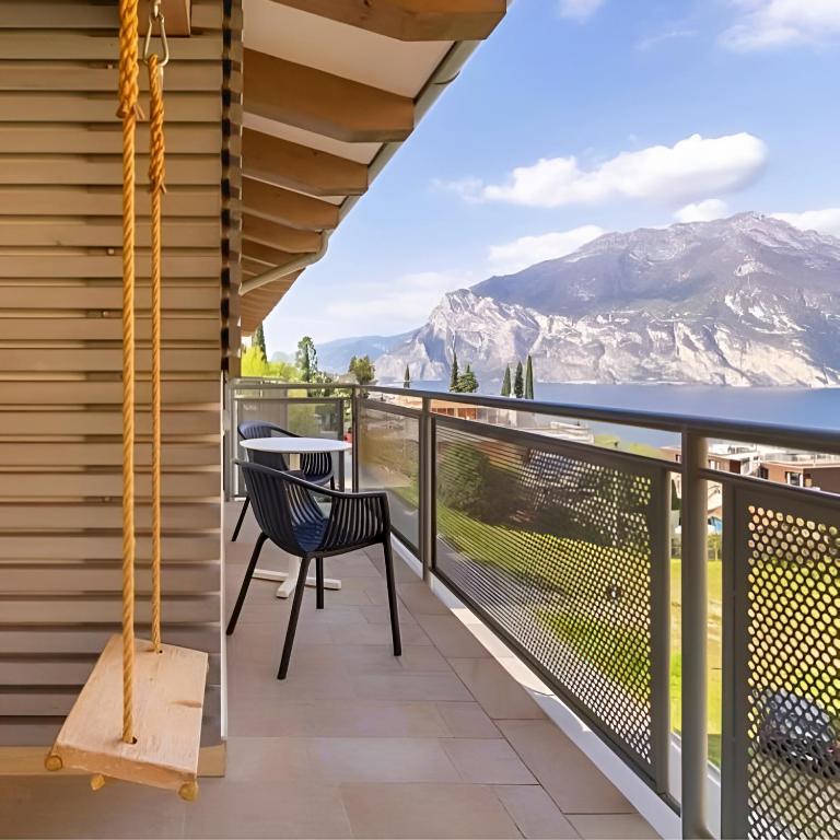 a balcony with a table and chairs and mountains at MySEELE Garda Active Hotel in Nago-Torbole