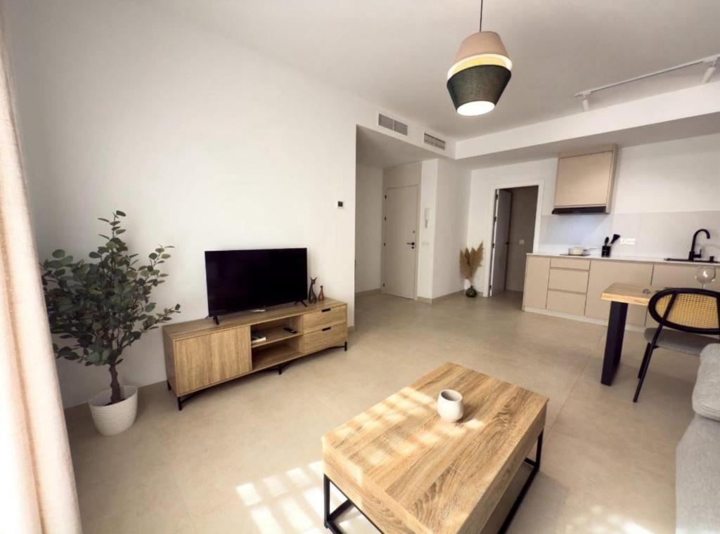 a living room with a flat screen tv and a table at Elegante Apartamento de 1 Dormitorio en Nerja in Nerja