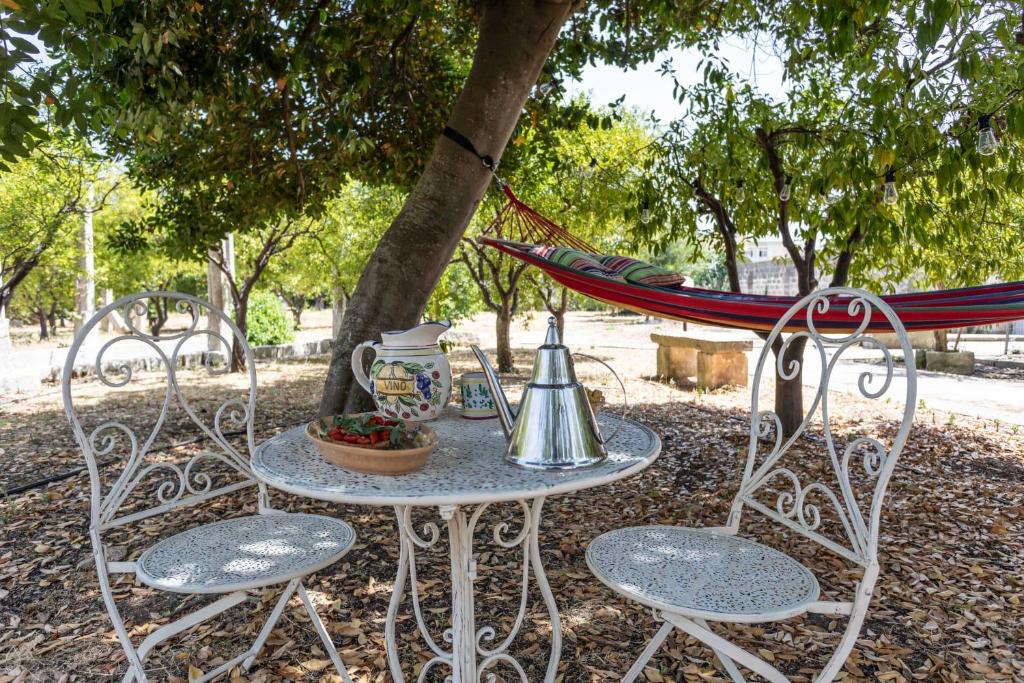 a table and chairs with a hammock in a park at Villa Ciccarese in Cursi