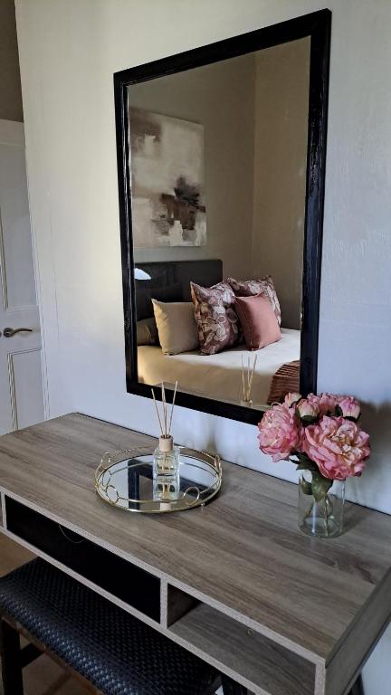 a mirror sitting on top of a table with flowers at Glen Lilly Self Catering in Parow