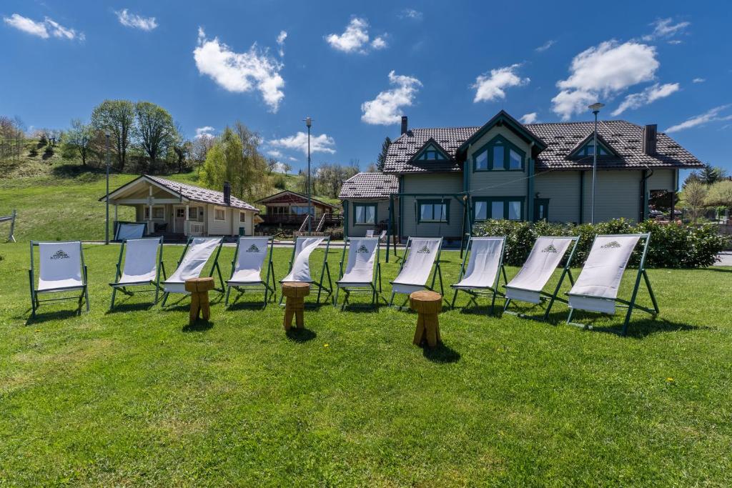 a row of chairs sitting in the grass in front of a house at Gorski park Kupjak in Kupjak