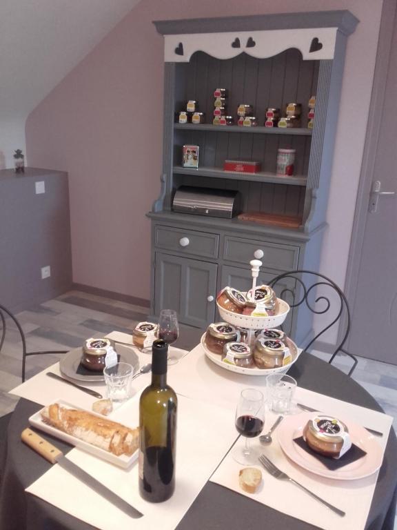 una mesa con una botella de vino y algo de comida en Jeanne et Compagnie en Loscouët-sur-Meu