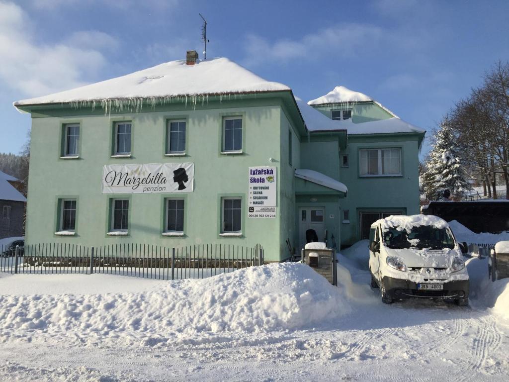 een auto geparkeerd voor een huis bedekt met sneeuw bij Guest House Marzebilla Pernink in Pernink