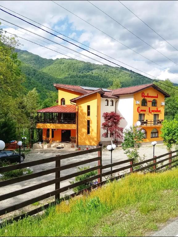 a yellow house with a fence in front of it at Pensiunea Restaurant Casa Lacului in Malaia