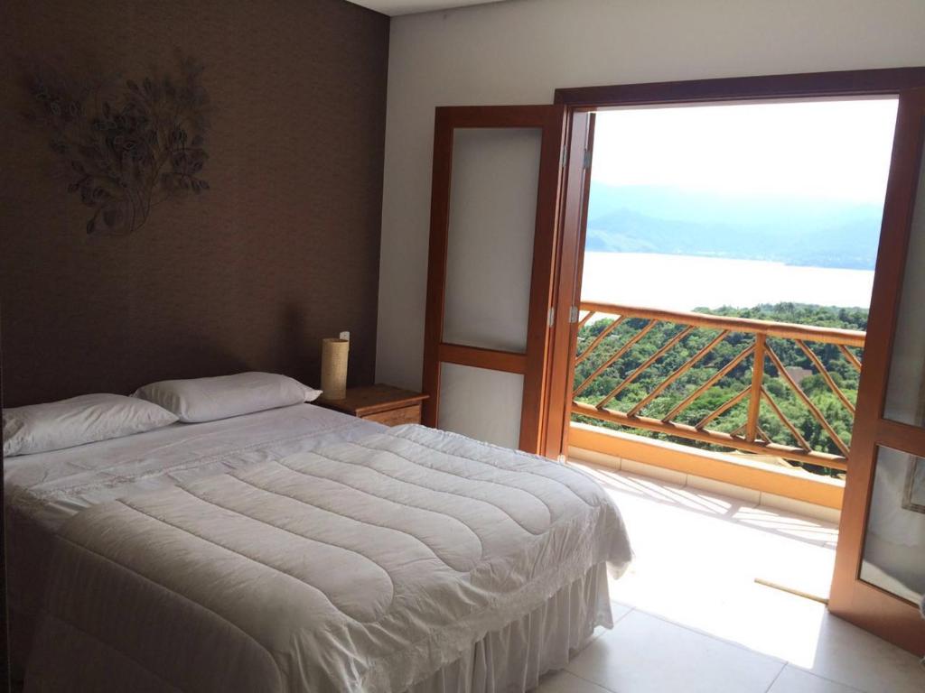 a bedroom with a bed and a large window at Casa de Luxo em Ilhabela vista para o Mar - Condominio Yacamin- Praia do Curral in Ilhabela