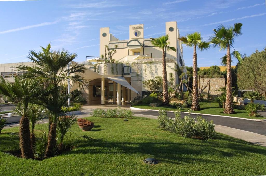 a large white house with palm trees and a street at Nicotel Barletta in Barletta