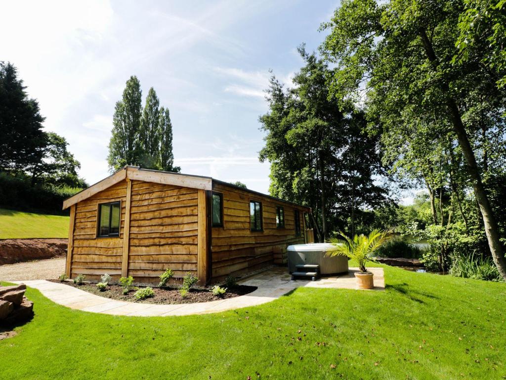 a small wooden cabin in a grassy yard at Kingfisher in Ross on Wye