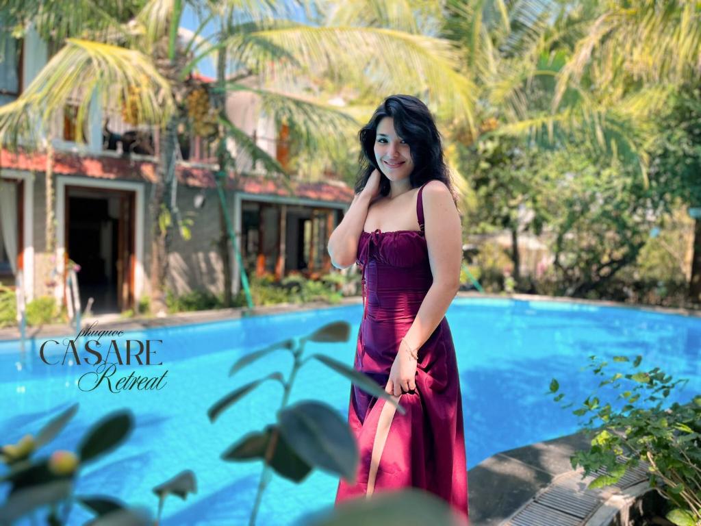 a woman in a red dress standing in front of a pool at Casare Retreat Phu Quoc in Phú Quốc