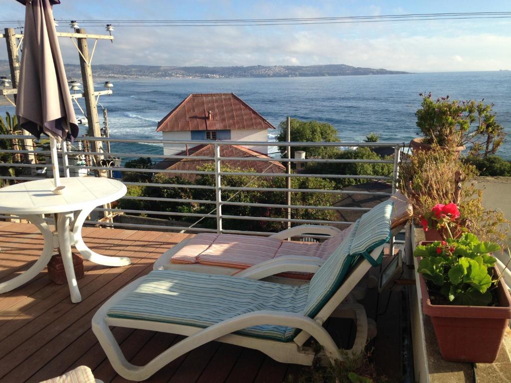 um deque com uma cadeira, uma mesa e um guarda-chuva em Hostal La Casa Barco em Las Cruces