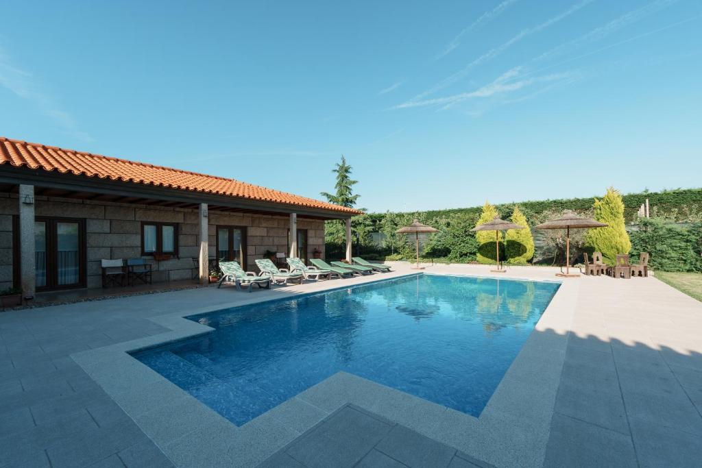 a pool with chairs and umbrellas next to a house at Feel Discovery Maçã Douro in Armamar