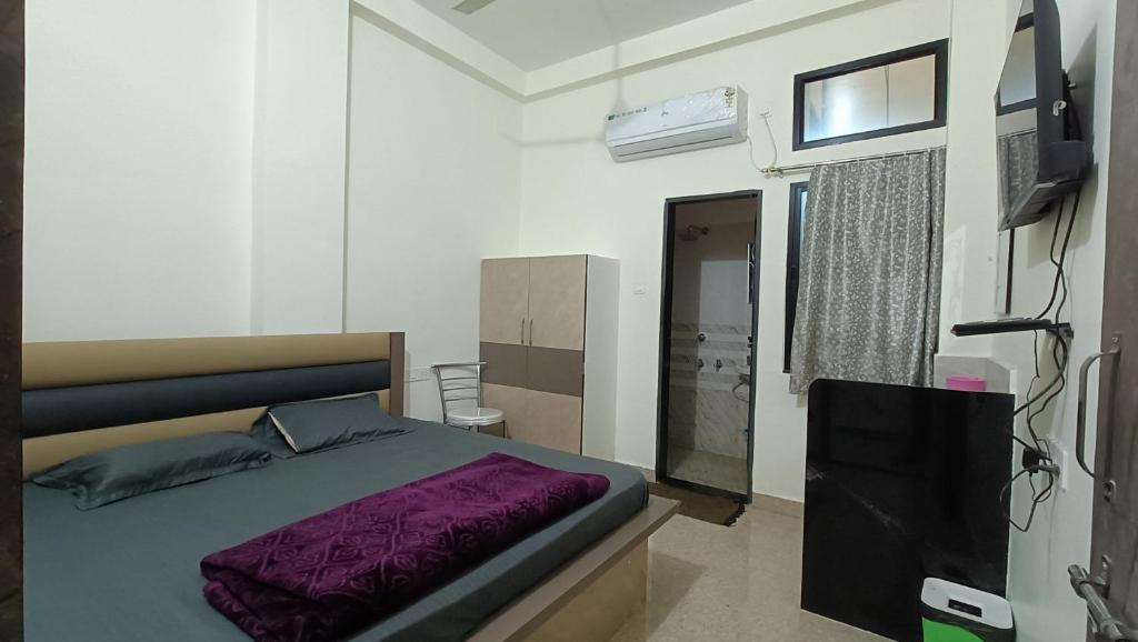 a bedroom with a bed with a purple blanket at Hotel Deeksha in Mandlā