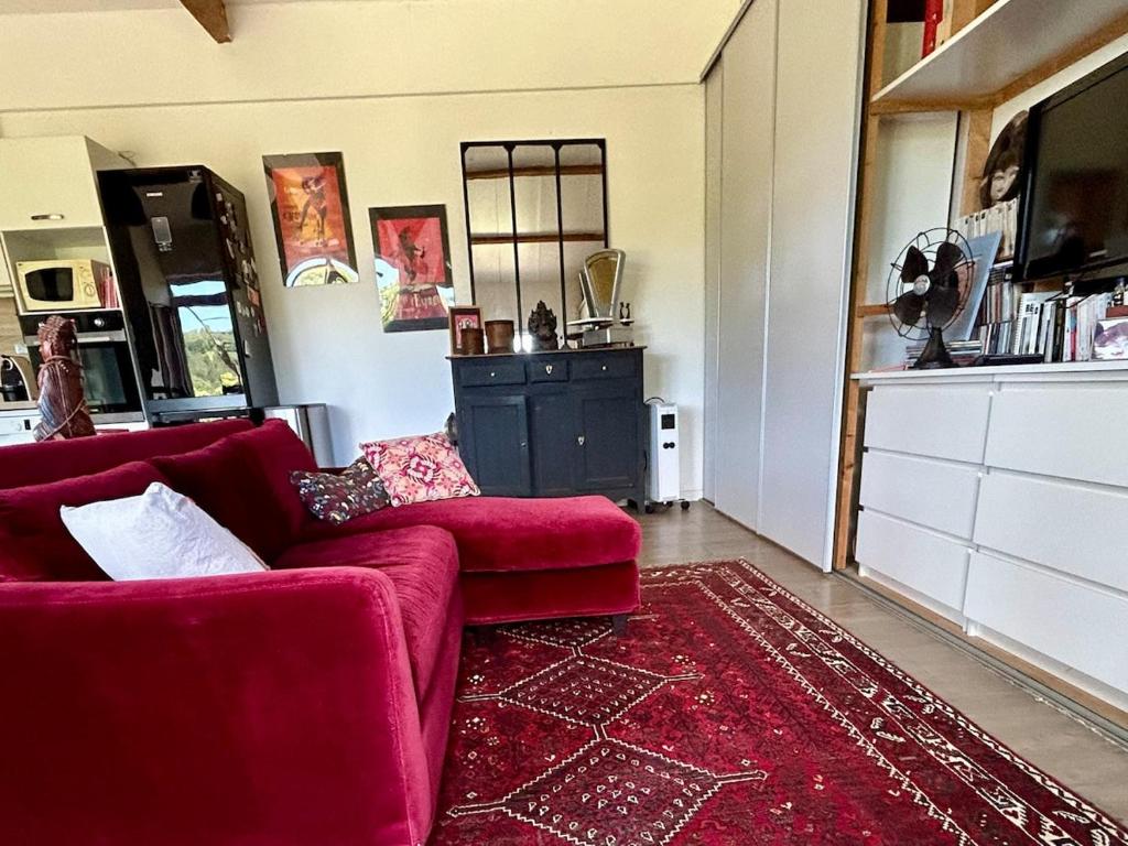 a living room with a red couch and a red rug at ATELIER Gîte Cahors in Pradines