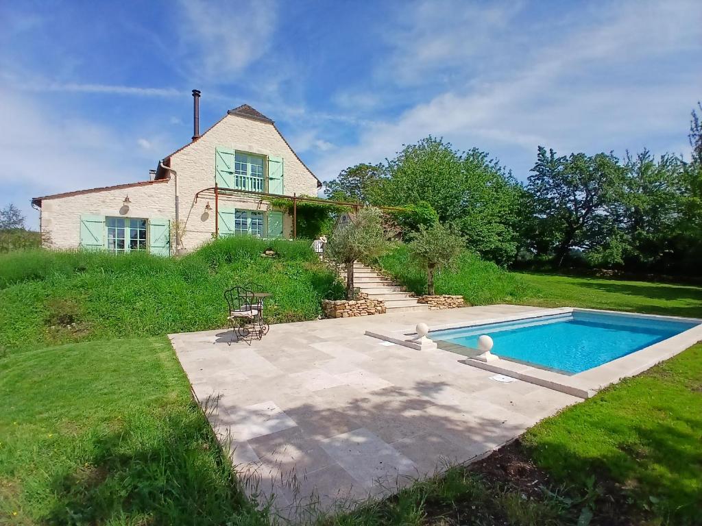 a house and a swimming pool in front of a house at Les Volets Verts-Dordogne in Plazac