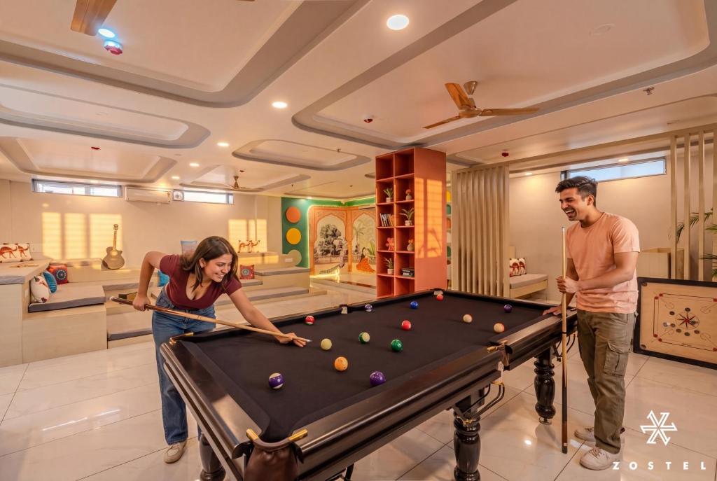 a man and a woman playing pool in a room at Zostel Jaipur, MI Road in Jaipur