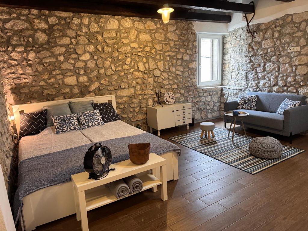 a bedroom with a bed and a stone wall at Old Town Apartment in Krk