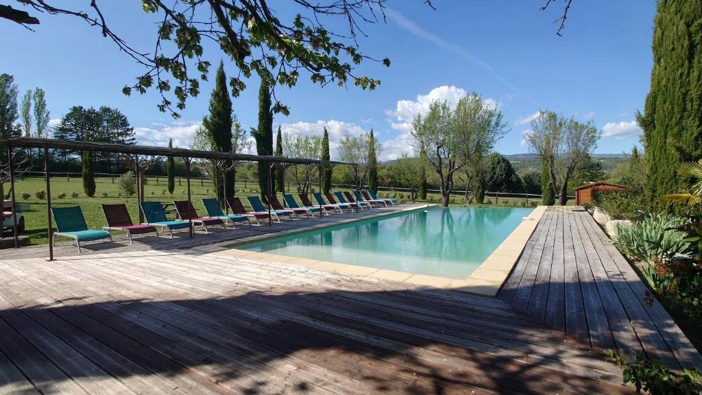 a swimming pool with lounge chairs on a wooden deck at Les Maisons De Chante Oiseau, Maisons, Lodges, Tentes et Cabane in Sigonce