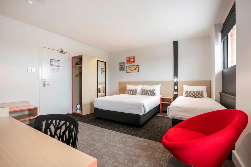 a hotel room with two beds and a red chair at Nightcap at Camp Hill Hotel in Brisbane