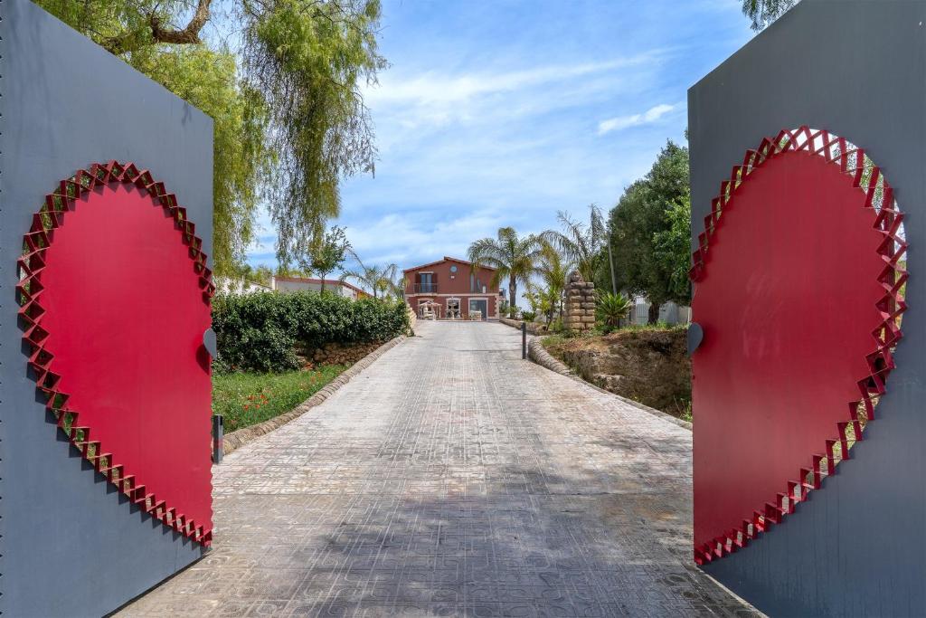 a gate with two red hearts on a road at Jungle Holiday Apartment in Avola