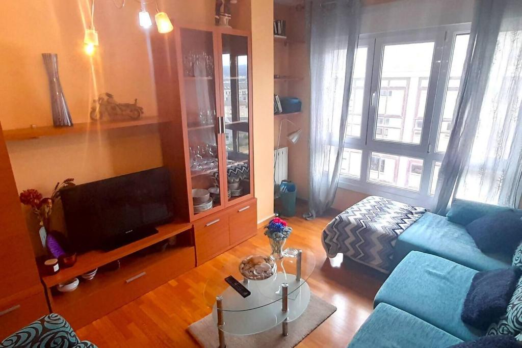 a living room with a blue couch and a tv at Apartamento Playa Foz in Foz