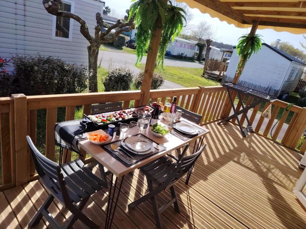 a table with food and drinks on a deck at MOBIL-HOME "B27" tout confort avec piscine & lave-linge gratuits in Mimizan