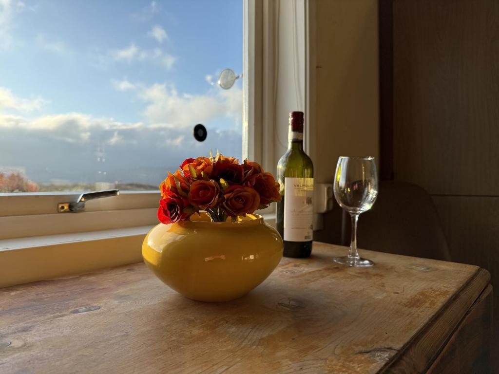 a bottle of wine and a vase with flowers and a glass at Charming house close to Lekens in Skullbru