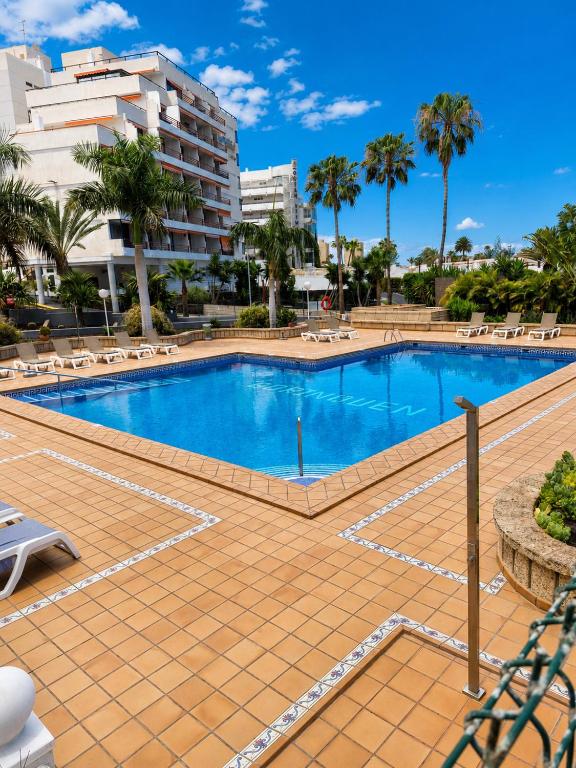 a large swimming pool with chairs and a building at 213 Borinquen Holiday in Costa de Adeje