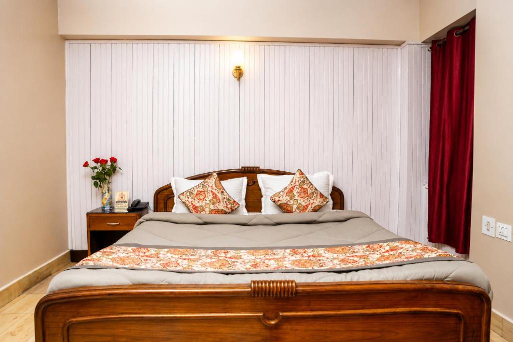 a bedroom with a wooden bed with red curtains at Hotel Red Rose in Darjeeling