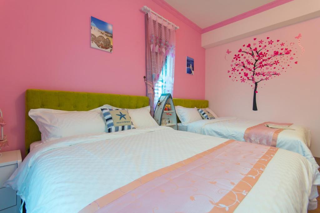 a bedroom with two beds and a tree on the wall at Greek Wonderland B&amp;B in Hualien City