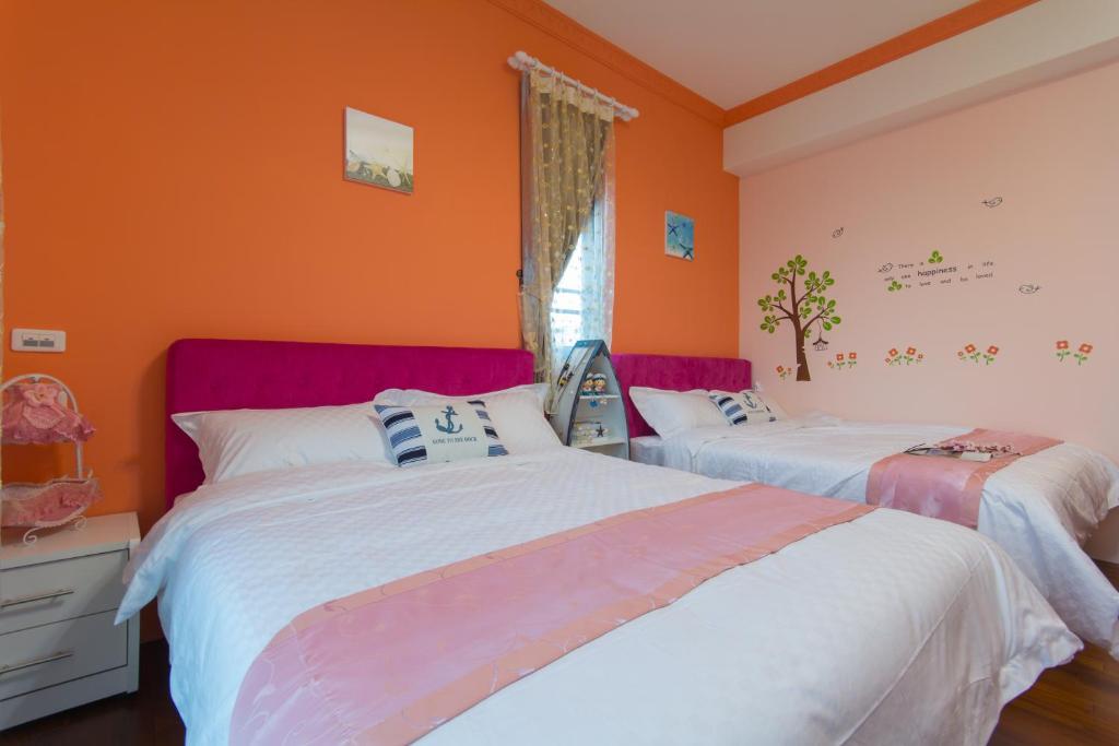 two beds in a room with orange walls at Greek Wonderland B&amp;B in Hualien City
