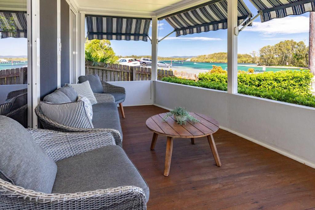 a porch with couches and a table and a view of the ocean at Summer Breeze Lake House in Forster