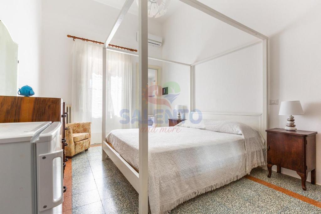 a white bedroom with a canopy bed and a dresser at Palazzo del Borgo Salentino in Acquarica del Capo