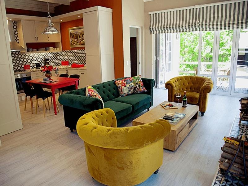 a living room with a green couch and a table at Romantic Boutique Cottage in upper Hogsback in Hogsback