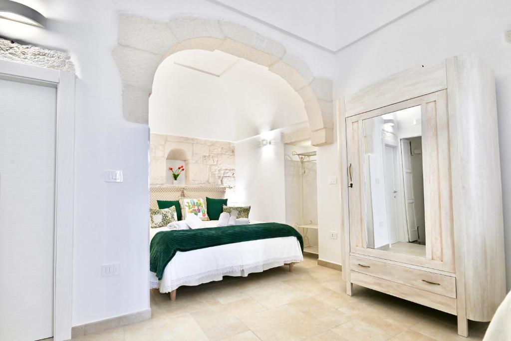 a white bedroom with a green bed and a mirror at Il Rifugio Dei Nonni in Ostuni