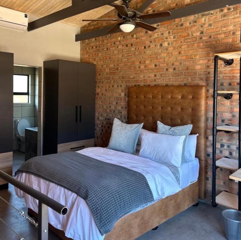 a bedroom with a large bed with a brick wall at Red Robin Guesthouse in Postmasburg