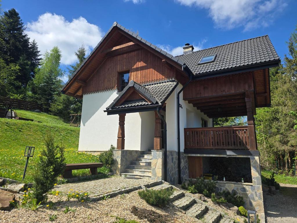a small house with a porch and a balcony at DOMEK POD CZEREMCHĄ, jacuzzi in Zawóz