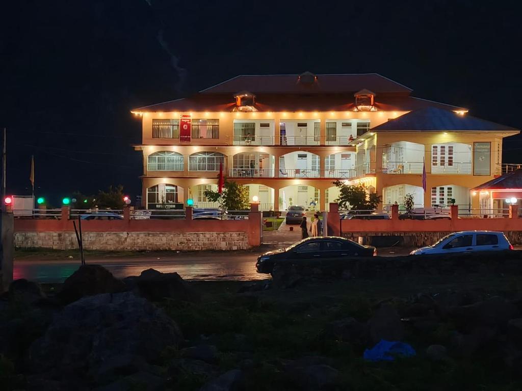 a large white building with lights on it at night at Stone Man's Hotel Samana Heights in Battakundi