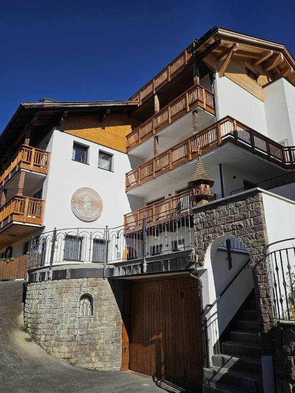 a building with a wooden gate and a building with stairs at Residence Stella Alpina in Santa Cristina Gherdëina