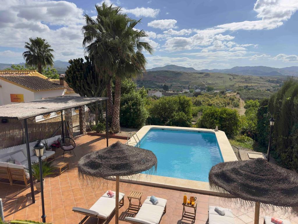 a swimming pool with chairs and umbrellas on a patio at Cortijo el Sendero in Alora
